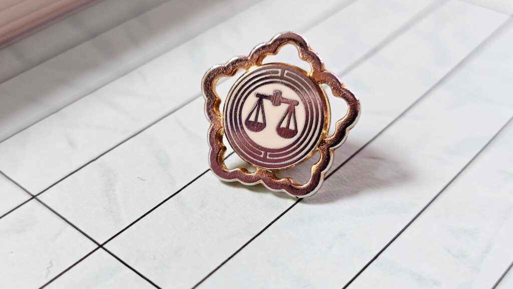 노트 위에 놓여있는 변호사 배지를 촬영한 이미지